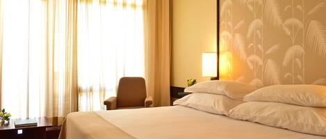 Une chambre d’hôtel avec un grand lit, une chaise, une table de chevet et une lampe.