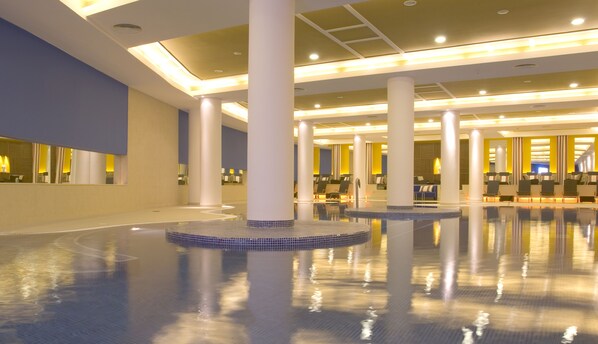 A spacious indoor swimming pool with multiple seating areas and a modern architectural design.