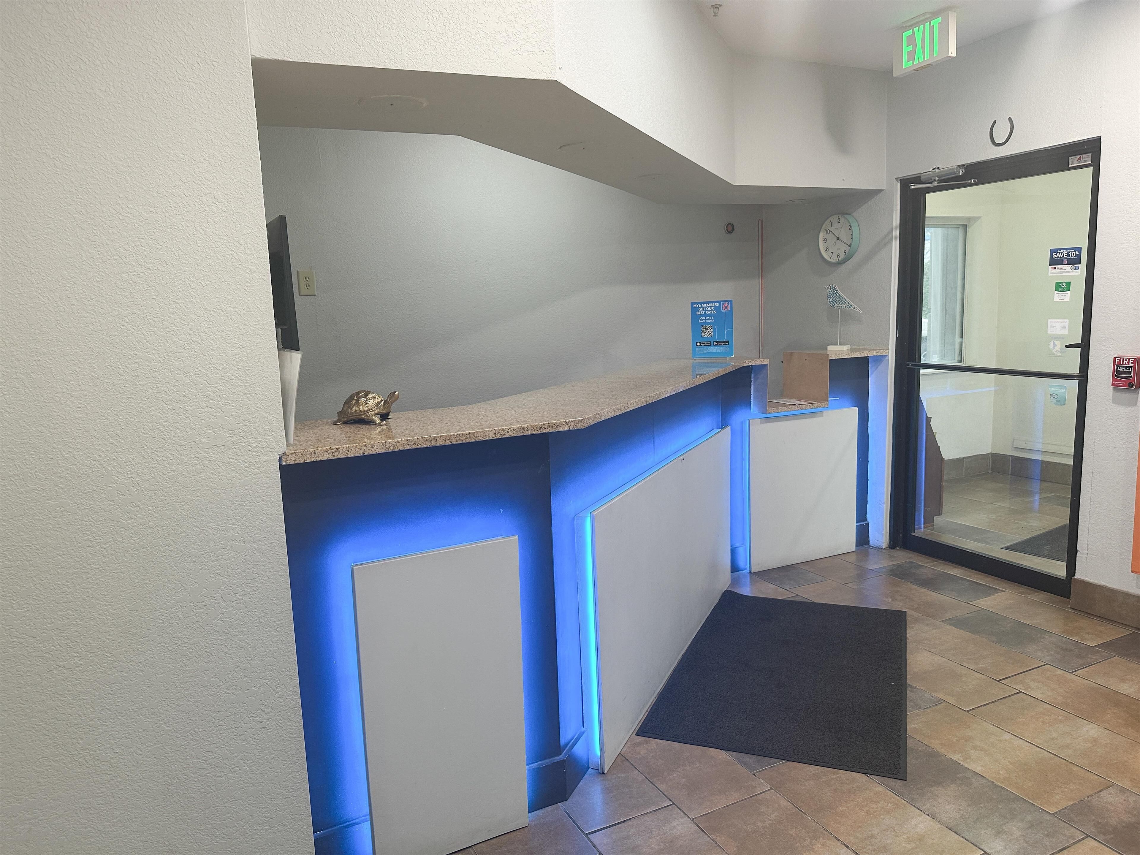 A reception desk with a blue accent wall, a clock, and a fire alarm on the wall.