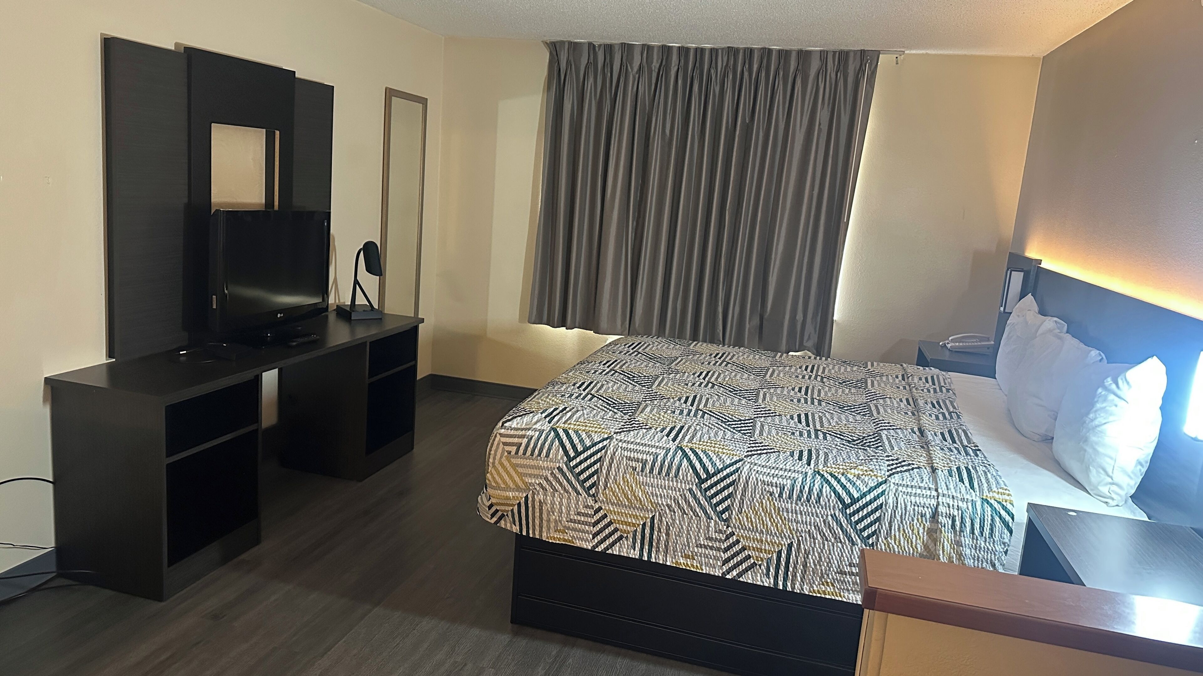 Habitación de hotel con cama, televisor, escritorio y silla.
