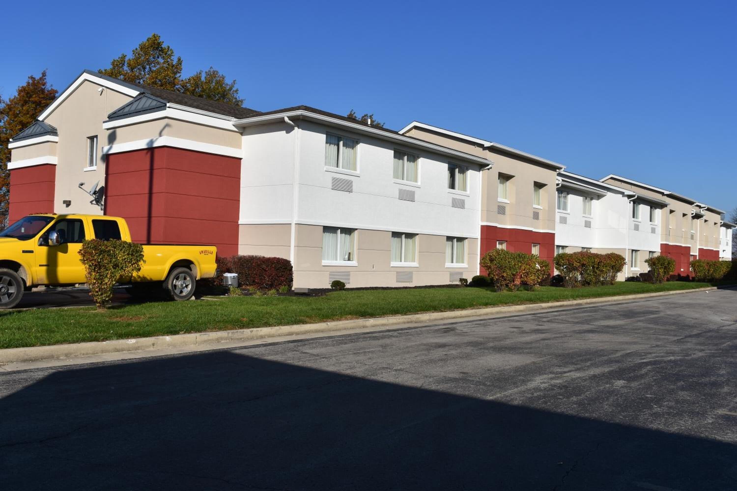 A row of modern, multi-story apartment buildings with a yellow truck parked in front.