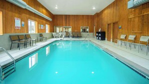 An indoor swimming pool with wooden walls, multiple lounge chairs, and a clear pool area. - Days Inn by Wyndham Evansdale Waterloo (Evansdale)