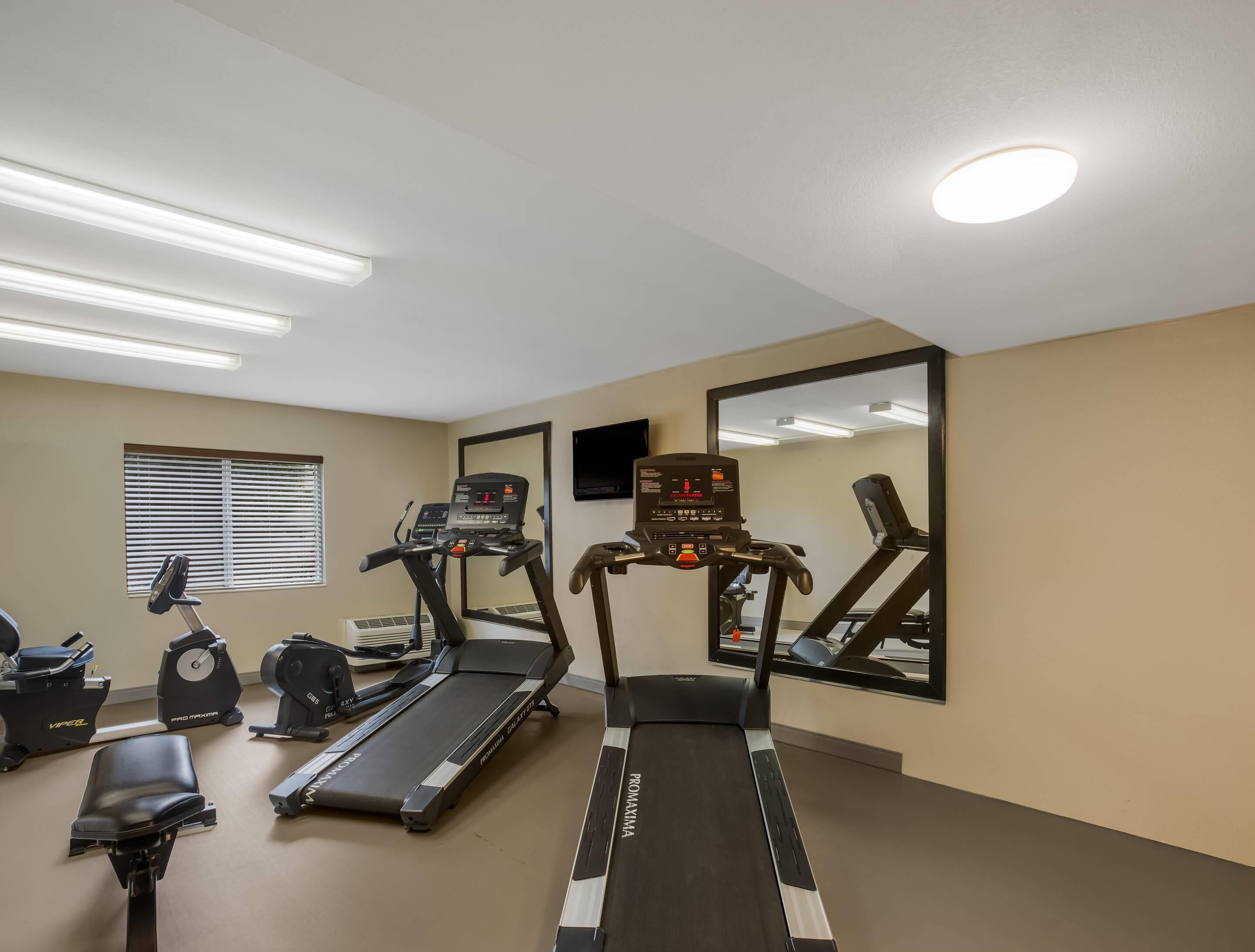 Un gimnasio con cintas de correr, una bicicleta estática y una máquina de remo.