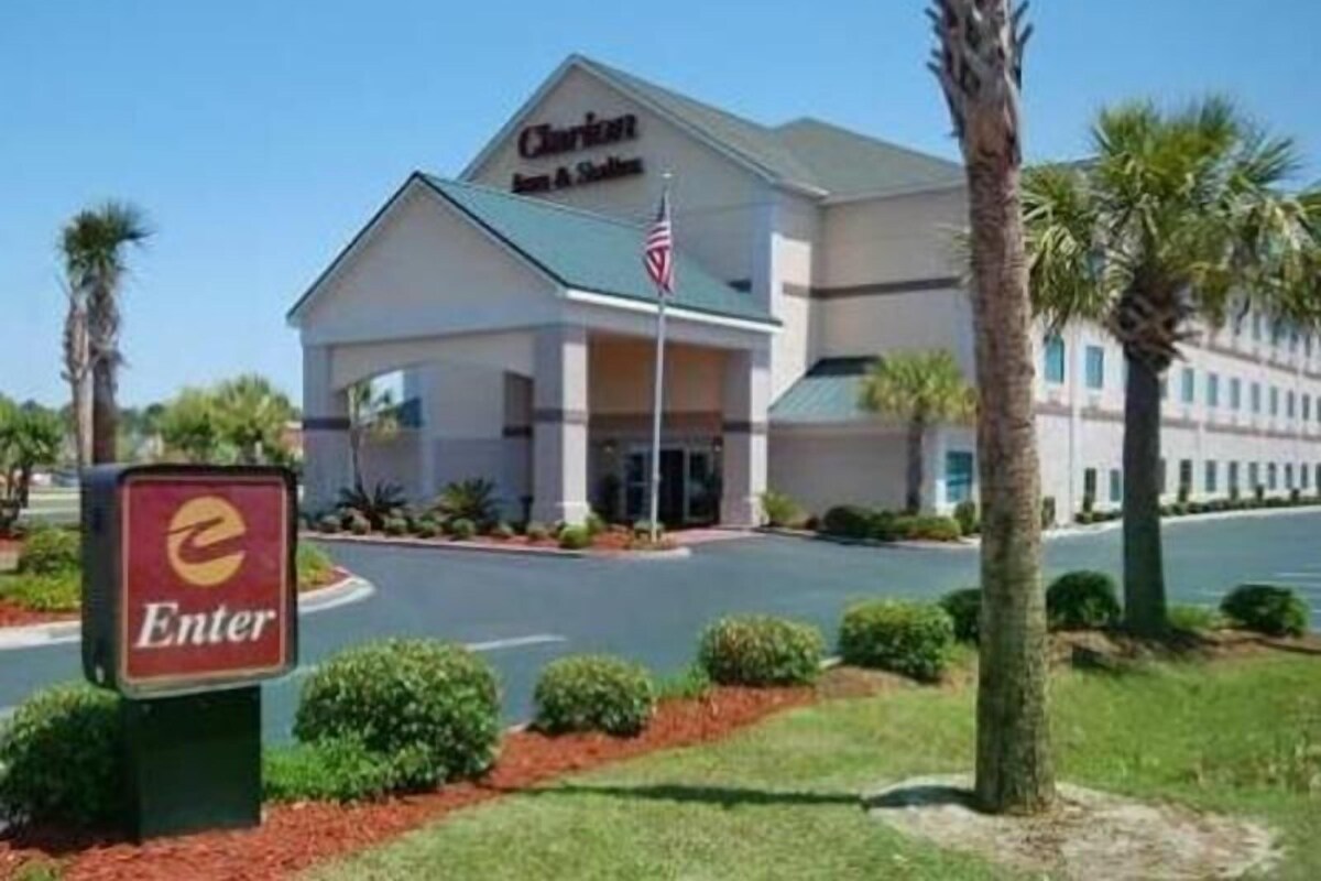 Un hôtel avec une enseigne indiquant « Clarion Inn & Suites » et un panneau « Entrée » devant.