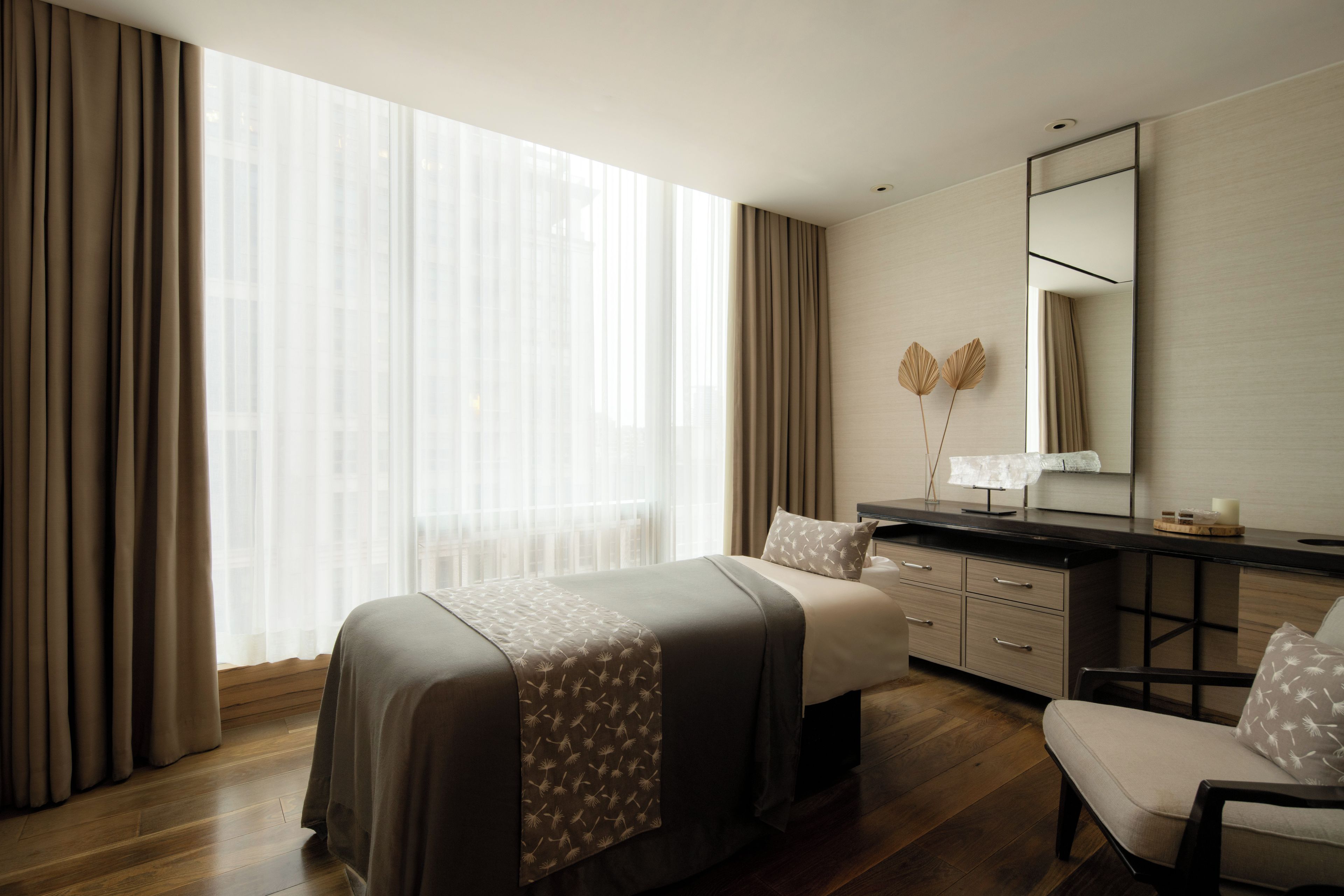 A hotel room with a large bed, a desk, and a chair.
