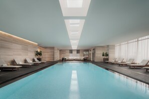 Relax by the serene pool surrounded by lounge chairs and lush greenery.
