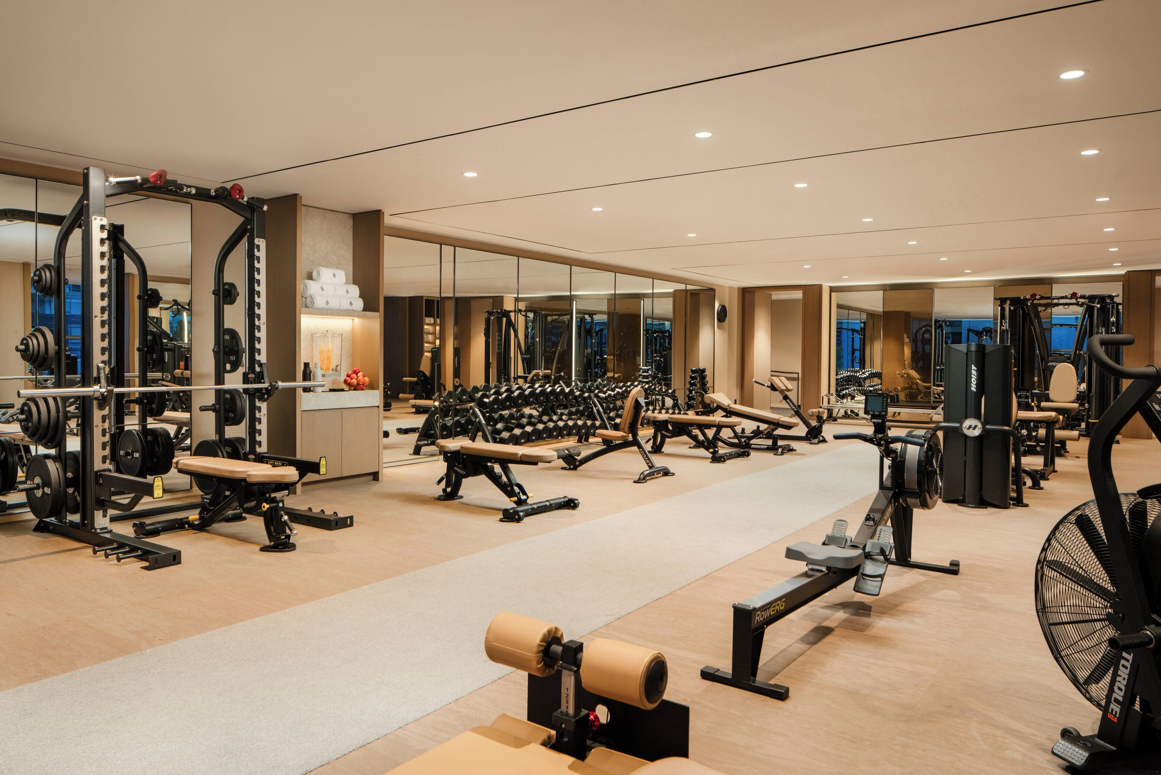 Un gimnasio con equipo de ejercicio diverso, espejos y suelo de madera.