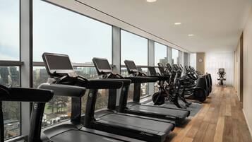 A row of stationary bikes in a high-rise building with large windows.