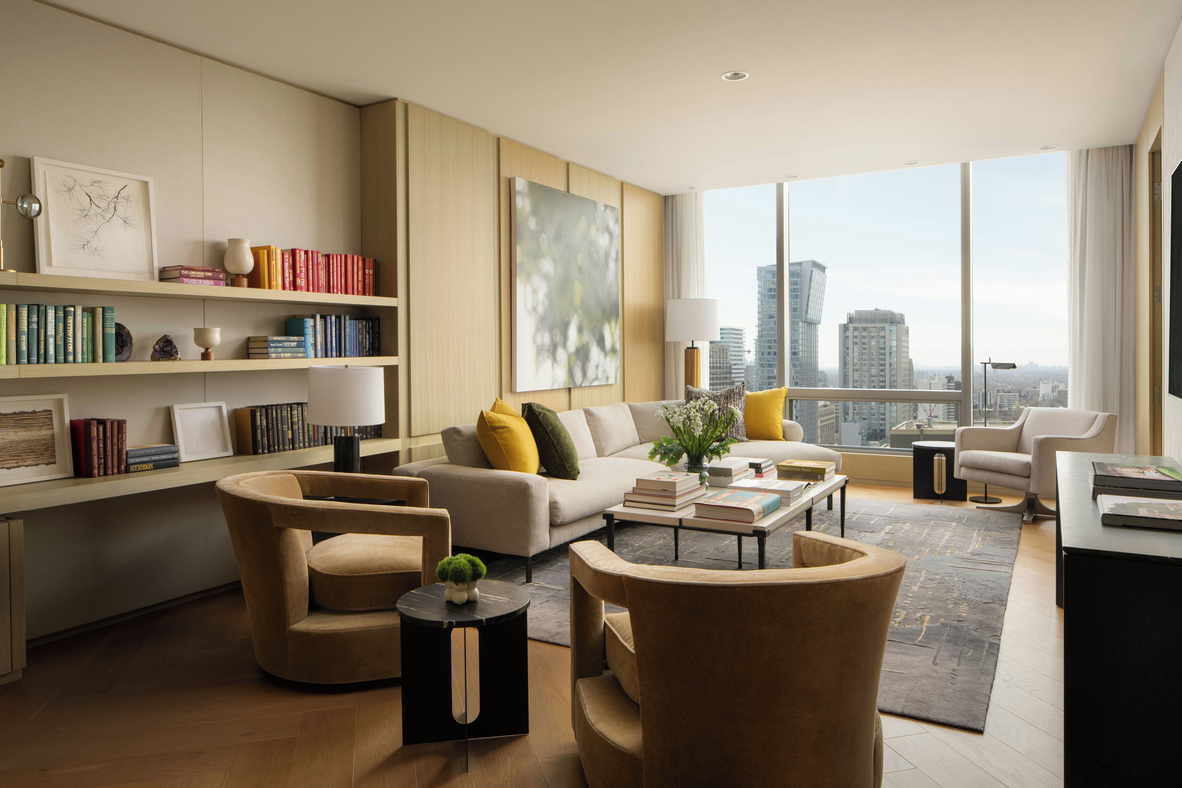 Een moderne woonkamer met een bank, fauteuils, een salontafel en een boekenkast.