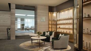 A modern lobby with a seating area, a reception desk, and a display of toiletries.