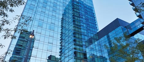 A modern high-rise building with reflective glass windows and a central fountain.