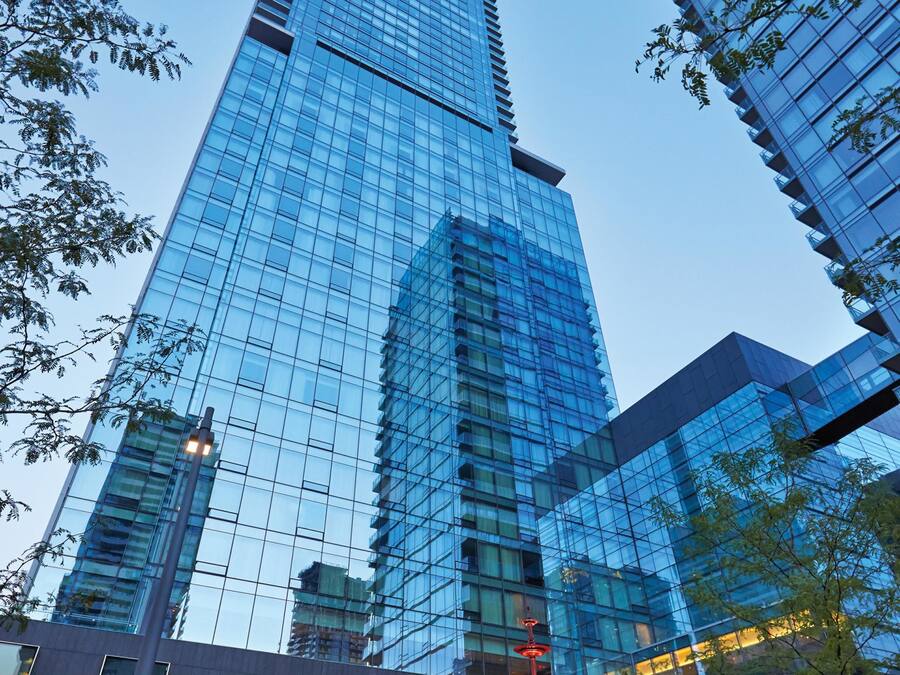 A modern high-rise building with reflective glass windows and a central fountain.
