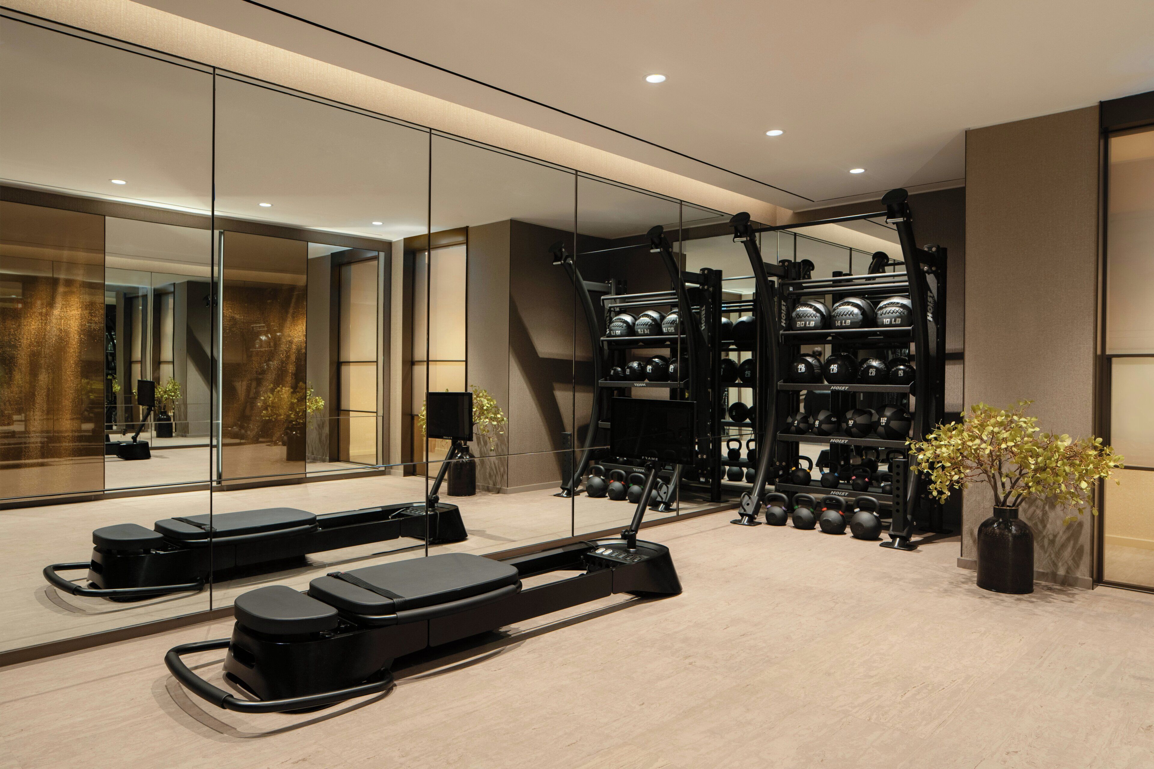 Une salle de sport moderne équipée de tapis de course, d’un rameur et d’un support à poids.