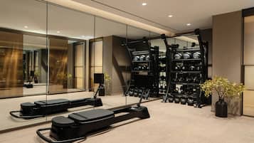 Une salle de sport moderne équipée de tapis de course, d’un rameur et d’un support à poids.