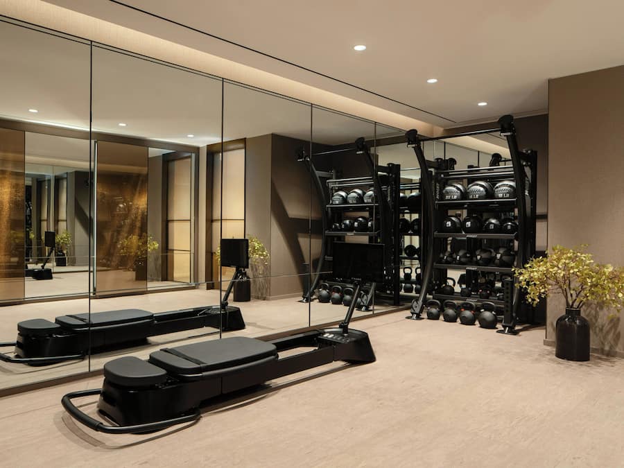 A modern gym with treadmills, a rowing machine, and a weight rack.