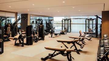 Ett modernt gym med olika typer av träningsutrustning, stora fönster och en ren och rymlig inredning.