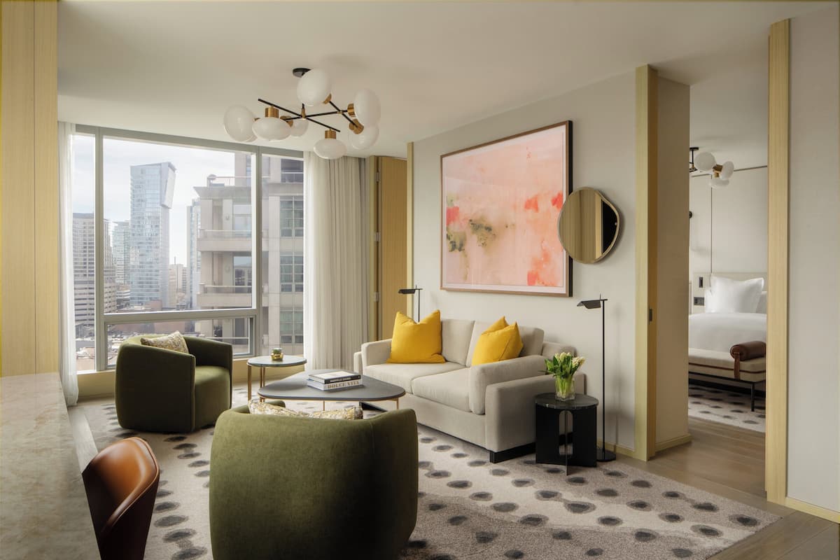 A modern living room with a sofa, armchairs, a coffee table, and a large window.