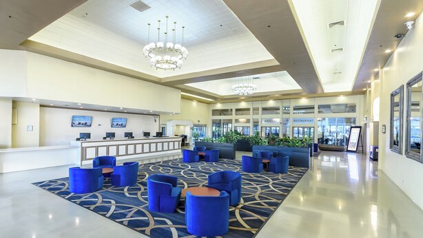 A spacious lobby with a reception desk, seating area, and a view of the restaurant and gardens. - Alexis Park All Suite Resort (Las Vegas)