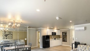 A spacious living area with a dining table and chairs, a kitchen with modern appliances, and a ceiling fan. - Alexis Park All Suite Resort (Las Vegas)