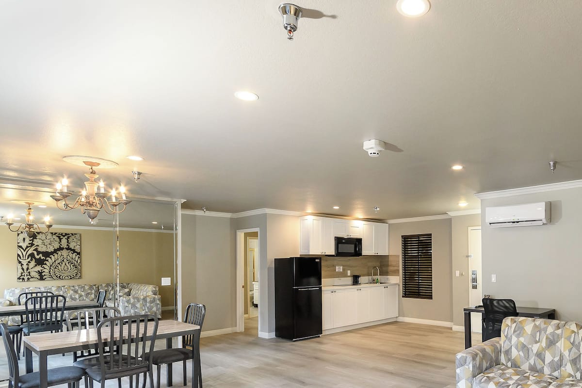 A spacious living area with a dining table and chairs, a kitchen with modern appliances, and a ceiling fan.