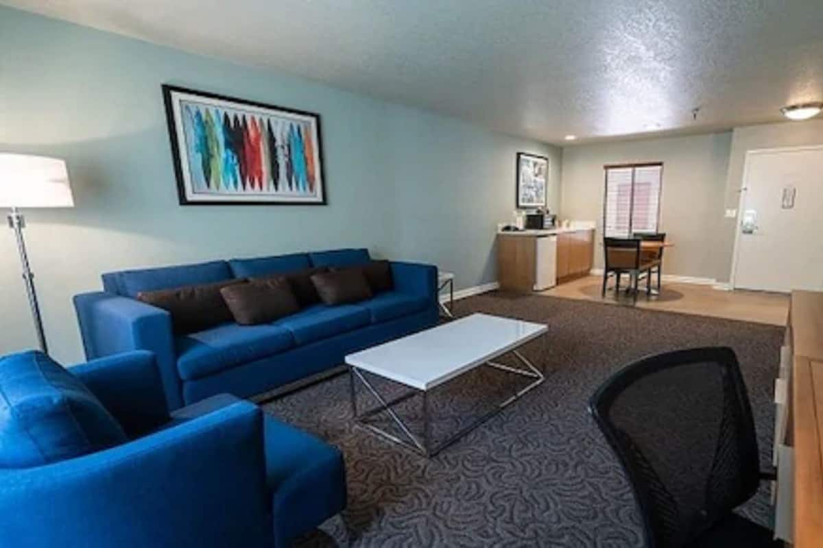 A living room with a blue sofa, a white coffee table, and a patterned carpet.