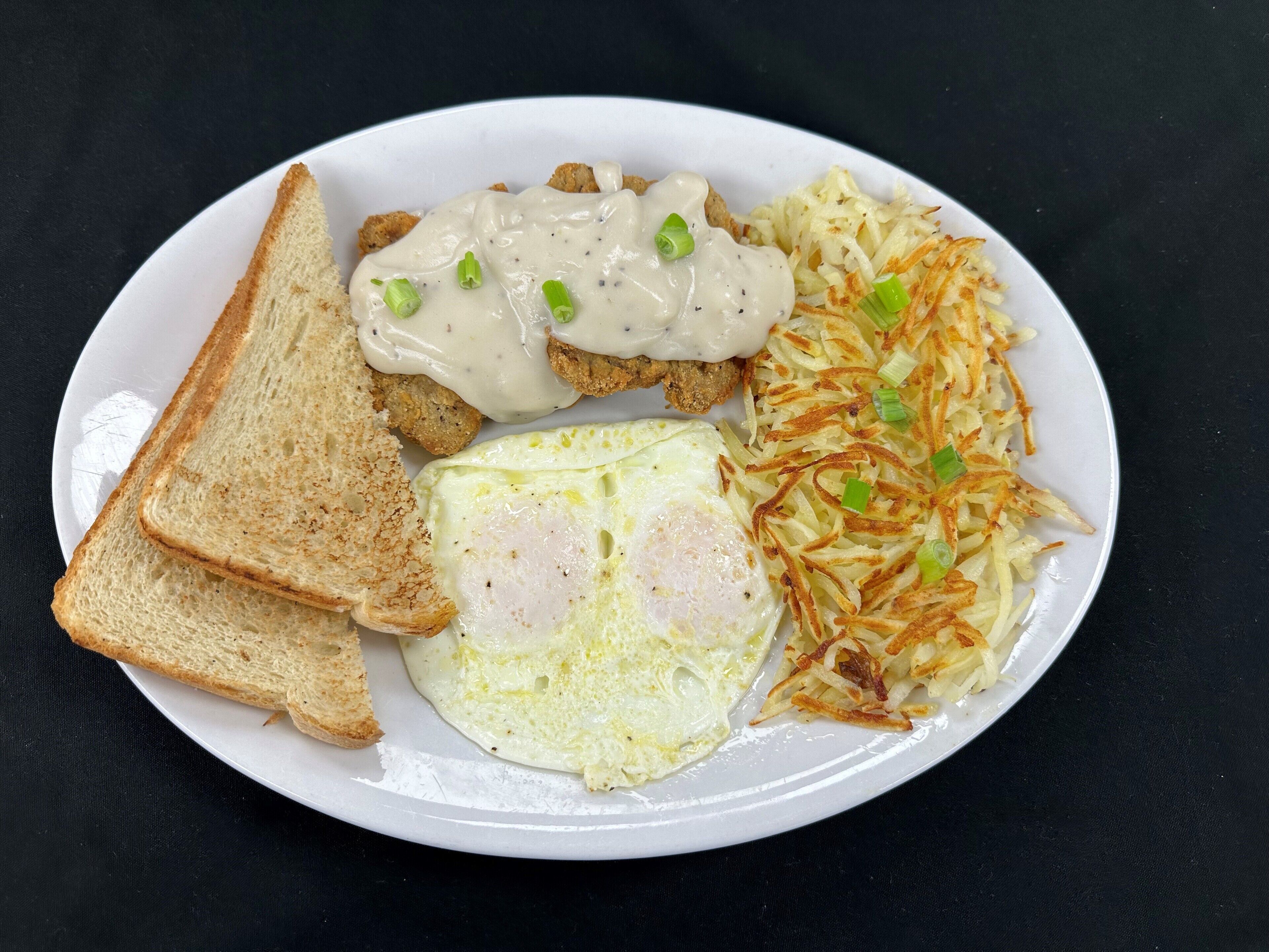 A plate with toast, eggs, and hash browns.
