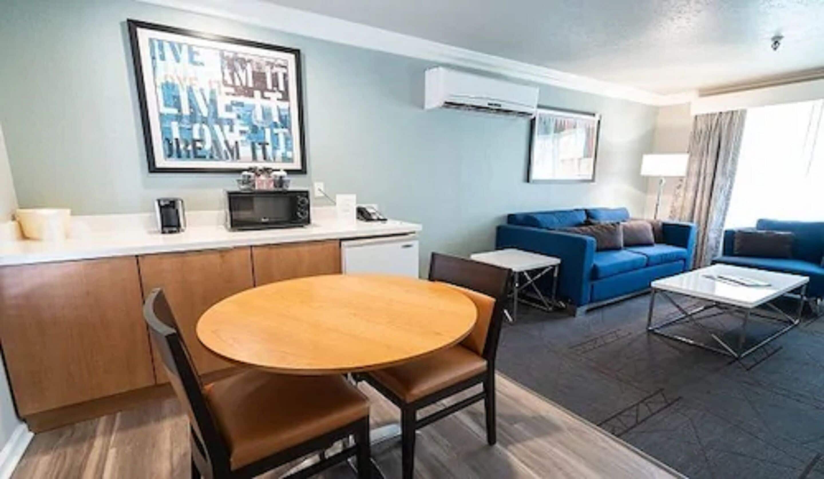 A compact living space with a kitchenette, a dining area, and a seating area with a blue sofa and a coffee table.
