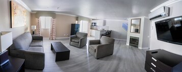 A modern living room with a grey sofa set, a coffee table, and a flat-screen TV.