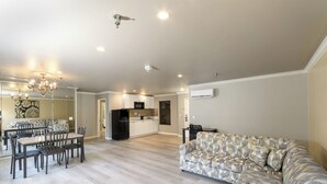 A spacious living area with a dining table, chairs, a sofa, and a kitchen in the background. - Alexis Park All Suite Resort (Las Vegas)