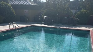 Una piscina cristalina con una señal de poca profundidad, un borde de ladrillo y una barandilla de metal.
