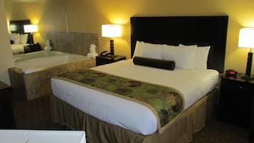 Una habitación de hotel con una cama grande, un baño separado con bañera y dos lámparas de noche.