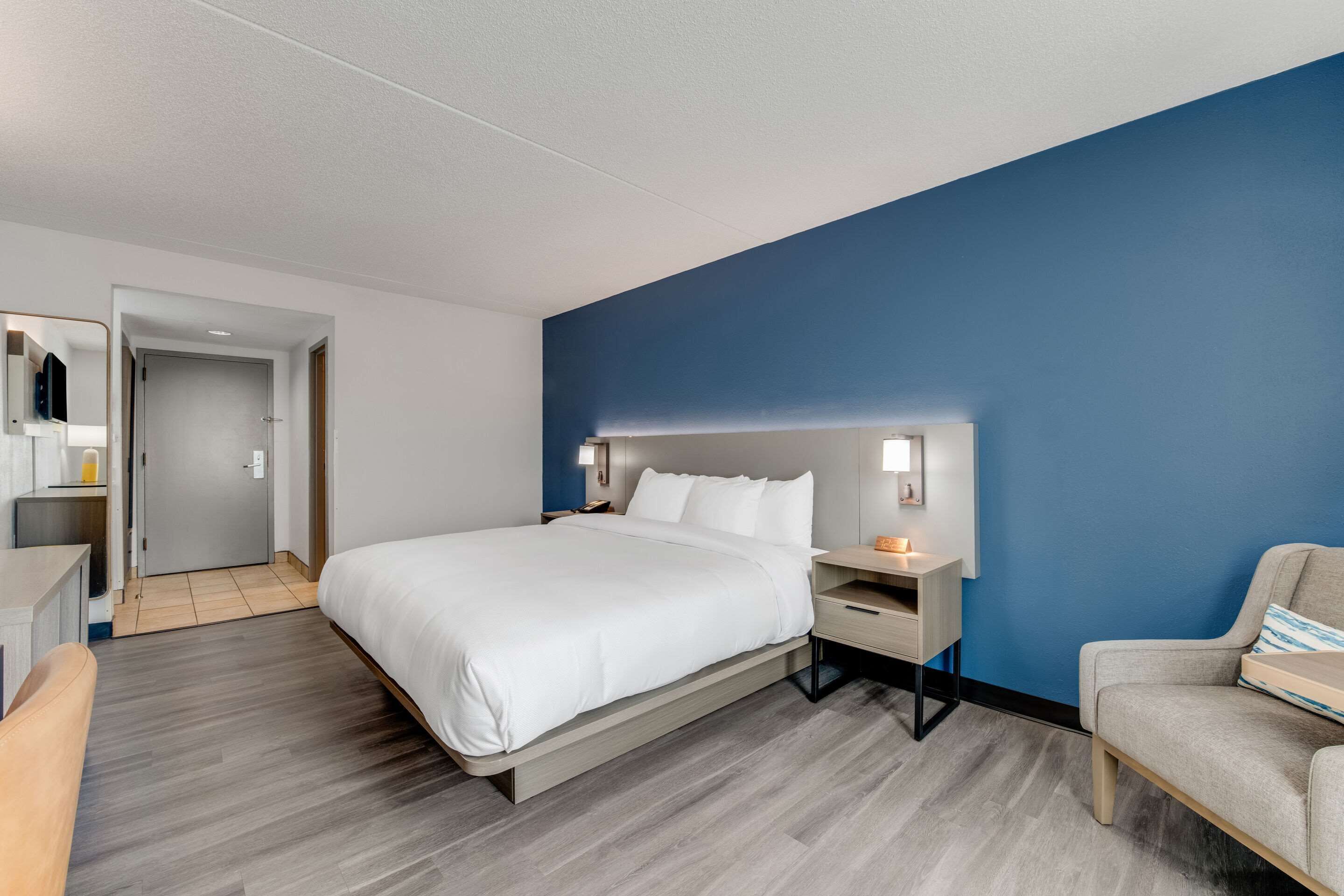 Una habitación de hotel moderna con una cama grande, mesitas de noche, un escritorio y una silla.