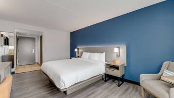 Una habitación de hotel moderna con una cama grande, mesitas de noche, un escritorio y una silla.