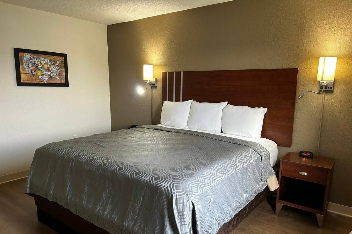 A hotel room with a large bed, two bedside lamps, a nightstand, and a wall-mounted painting.