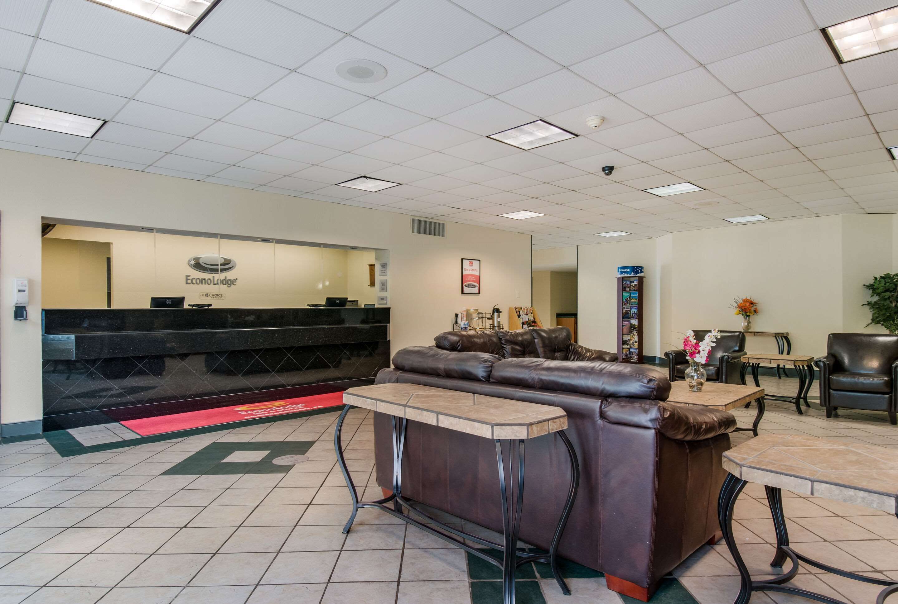 A lobby with a reception desk, leather sofas, a coffee table, and a small dining area.