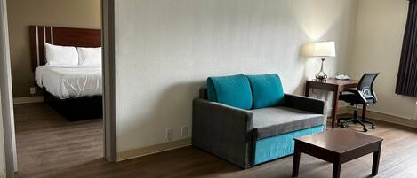 Una habitación de hotel con una cama, un sofá, un escritorio y una lámpara.