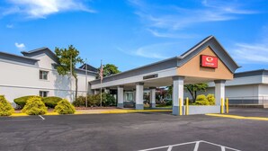 Un hotel con entrada cubierta, un letrero que indica 10 minutos de despeje y un estacionamiento.