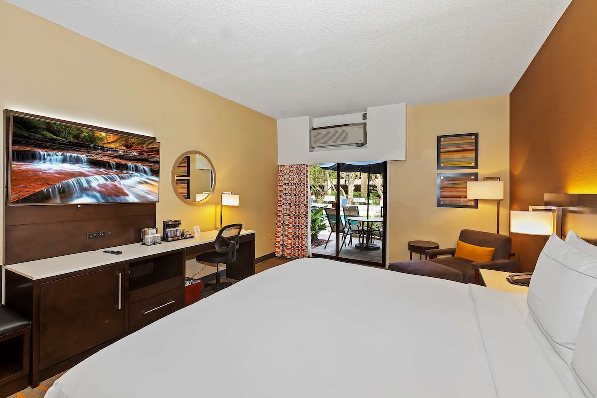 Une chambre d’hôtel avec un grand lit, un bureau avec une chaise, une télévision et une vue sur l’espace extérieur.