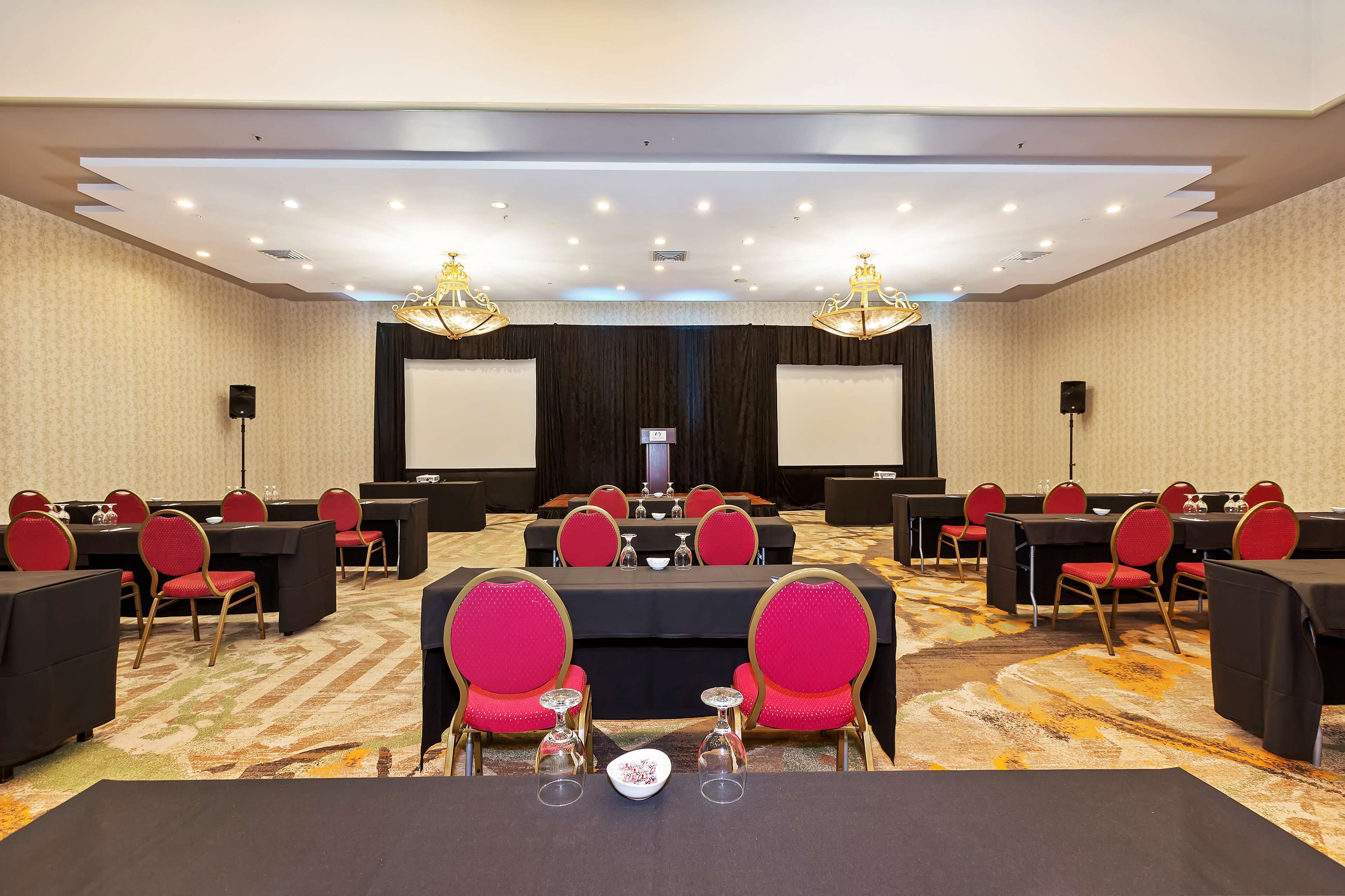A conference room with tables and chairs, a projector screen, and a carpeted floor.
