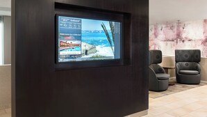 Pantalla digital en el vestíbulo de un hotel con vista a una playa y al océano.
