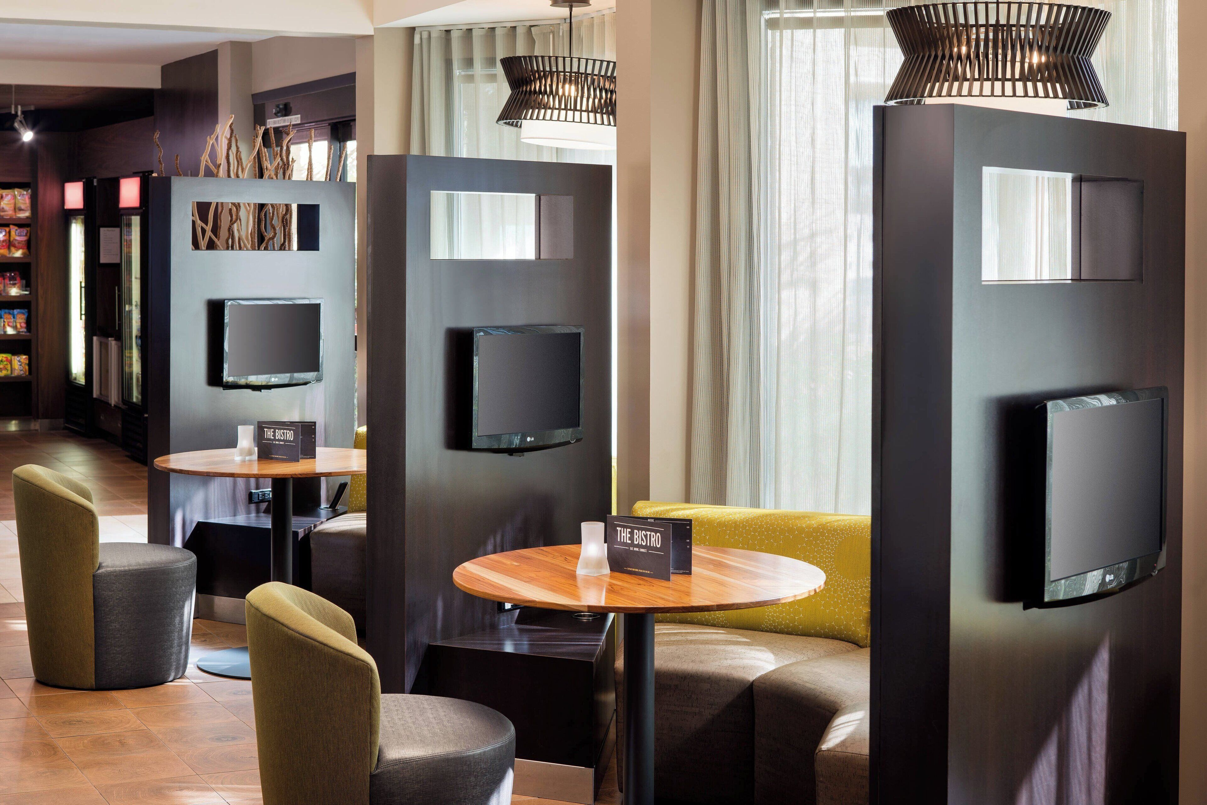 Eine moderne Hotelhalle mit Barbereich, Sitzgelegenheiten und einem an der Wand montierten Fernseher.