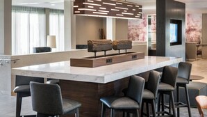 Un bar moderno con mostrador de mármol, taburetes de madera y una lámpara colgante original.