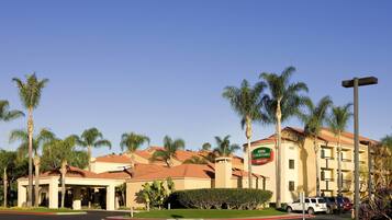 Un hotel Courtyard Marriott con entrada cubierta, palmeras y estacionamiento.