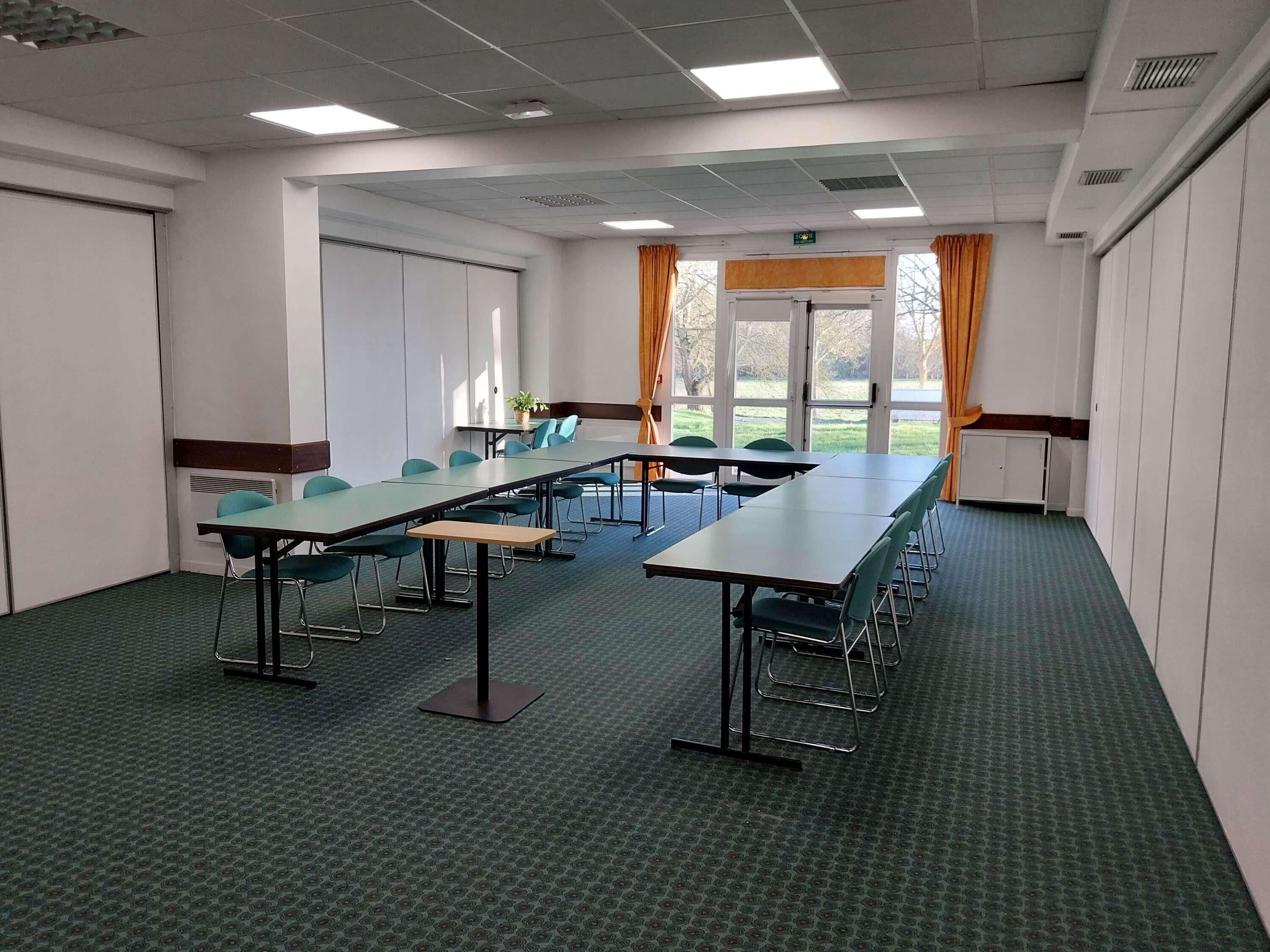 Un salón de conferencias con mesas largas, sillas y vistas amplias a través de grandes ventanales.