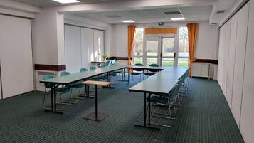 Un salón de conferencias con mesas largas, sillas y vistas amplias a través de grandes ventanales.