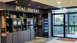 Un mercado pequeño con un letrero que dice 'HOME', estantes con productos y una máquina expendedora.