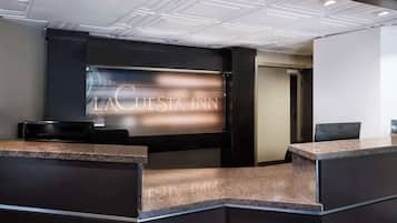 A reception desk with a modern design, featuring a dark color scheme and a glass partition displaying the name "LA CUESTA INN".