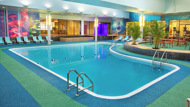 An indoor swimming pool with blue and green artificial turf, lounge chairs, and a mural of marine life on the walls. - Sheraton Niagara Falls (Niagara Falls)