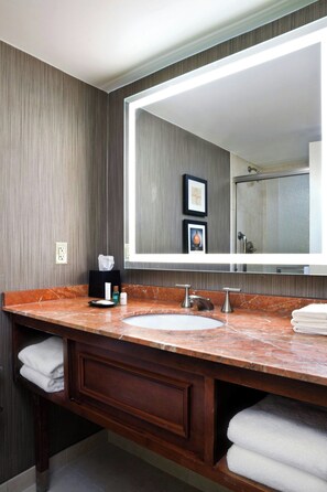 A bathroom with a large mirror, a sink, and a vanity with a towel rack.
