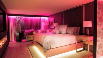Un dormitorio moderno con una cama grande, lámparas de noche, una mesita de noche y un televisor de pared.